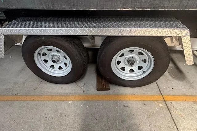 Slide: The Image of Trailer wheels of a 2001 Edgewater 225CC boat, parked on concrete. - 16