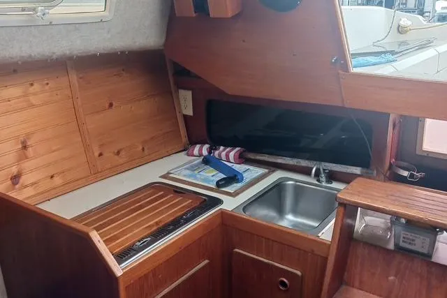 Slide: The Image of 1989 O'Day 272 sailboat interior kitchen with wooden cabinetry and stainless steel sink. - 11