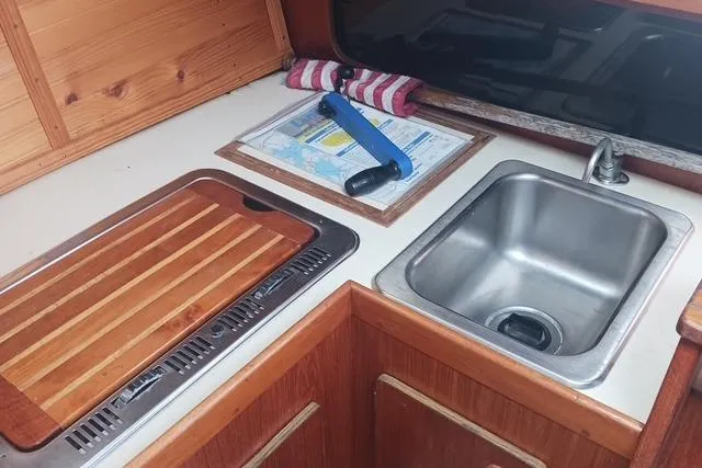 Slide: The Image of 1989 O'Day 272 sailboat galley with sink, cutting board, and nautical chart. - 13