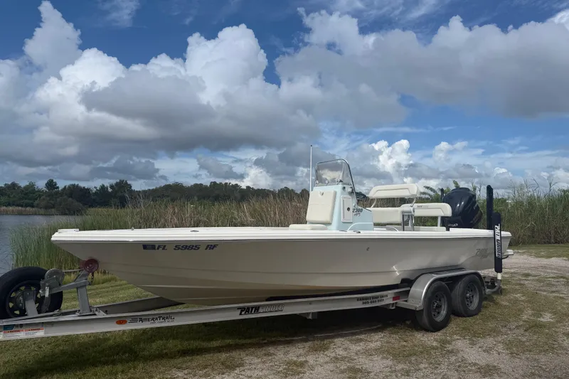 The Image of 2016 Pathfinder 2300 HPS boat on trailer, parked near a lake under cloudy sky. - 0