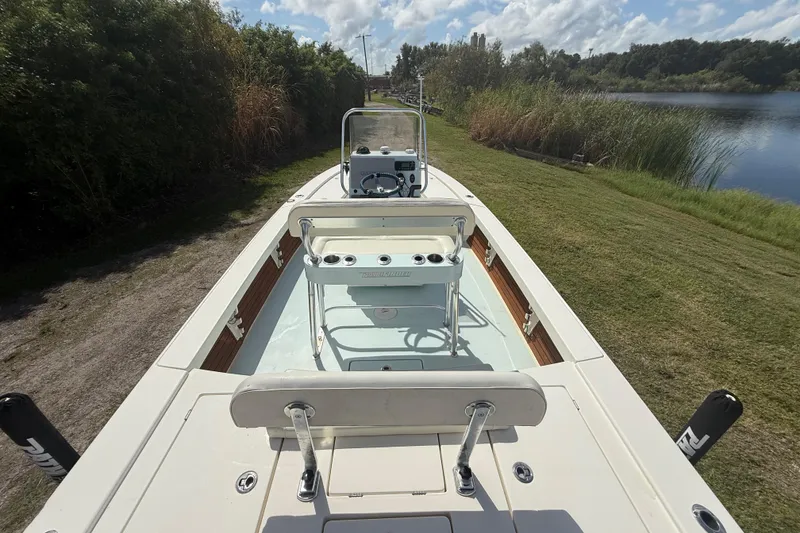 Slide: The Image of 2016 Pathfinder 2300 HPS boat on grassy shore, clear sky, and calm water. - 13
