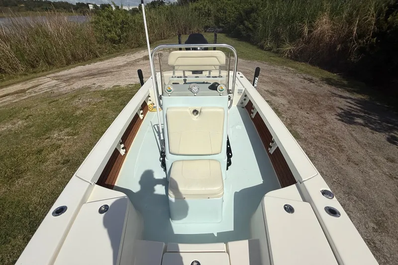 Slide: The Image of 2016 Pathfinder 2300 HPS boat interior with seating and console, parked on grassy area. - 20