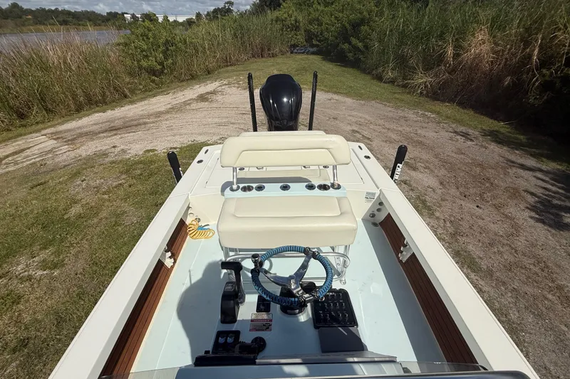 Slide: The Image of 2016 Pathfinder 2300 HPS boat interior with steering wheel and seating, parked on grassy terrain. - 21