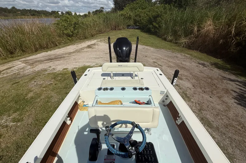 Slide: The Image of 2016 Pathfinder 2300 HPS boat interior with steering wheel, storage, and motor, near grassy shoreline. - 22
