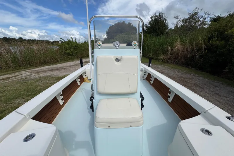 Slide: The Image of 2016 Pathfinder 2300 HPS boat interior with seating and console, surrounded by lush greenery. - 34