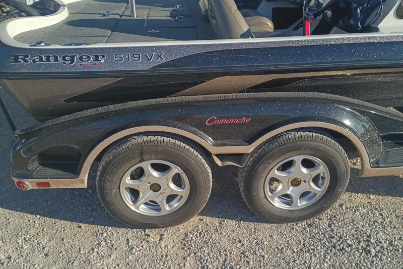 Slide: The Image of 2005 Ranger 519SVX Comanche boat trailer with dual wheels on gravel surface. - 6