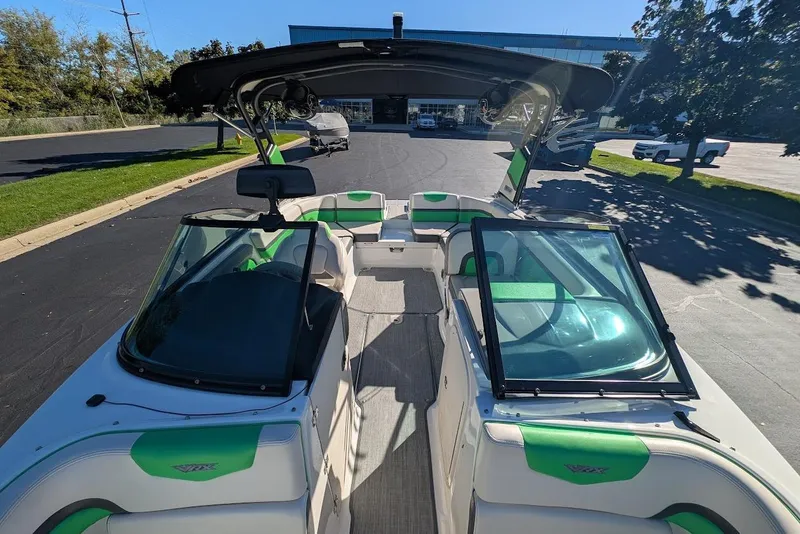 Slide: The Image of 2018 Chaparral Vortex 223 VRX boat with green accents, parked outdoors. - 13