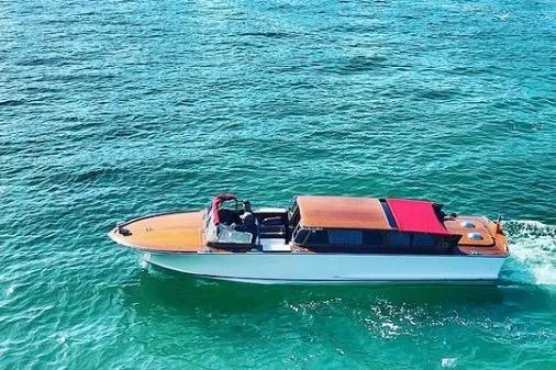 The Image of 2002 A&M Manufacturing Veneziano Convertible boat cruising on clear blue water. - 1