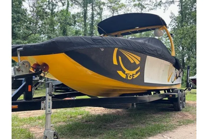 Slide: The Image of 2013 Tigé RZ4 boat with cover on trailer, yellow and black design, parked outdoors. - 3
