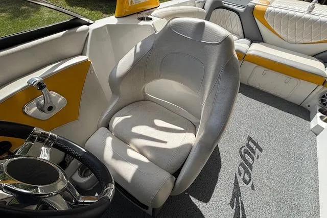 Slide: The Image of 2013 Tigé RZ4 boat interior with white and yellow seating, steering wheel, and logo carpet. - 8