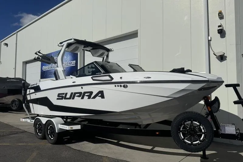 Slide: The Image of 2025 Supra SL 575 boat on trailer, parked outside a building. - 3