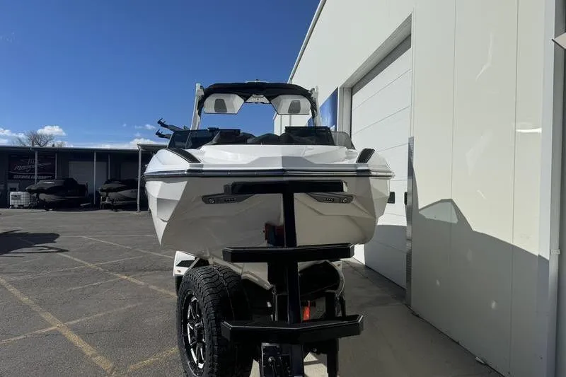 Slide: The Image of 2025 Supra SL 575 boat on trailer outside a building under clear sky. - 4