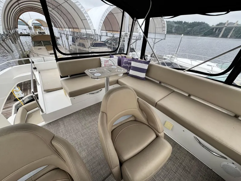 Slide: The Image of 2014 Carver C40 Command Bridge interior with seating and table, docked by the water. - 19