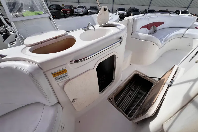 Slide: The Image of 2002 Chaparral 232 Sunesta boat interior with sink, storage, and seating area. - 15