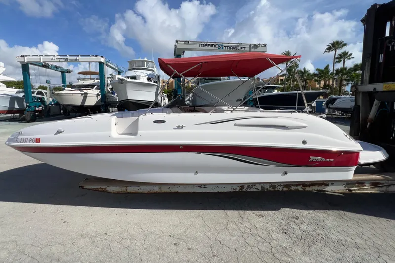 Slide: The Image of 2002 Chaparral 232 Sunesta boat with red accents and canopy, docked under blue sky. - 2
