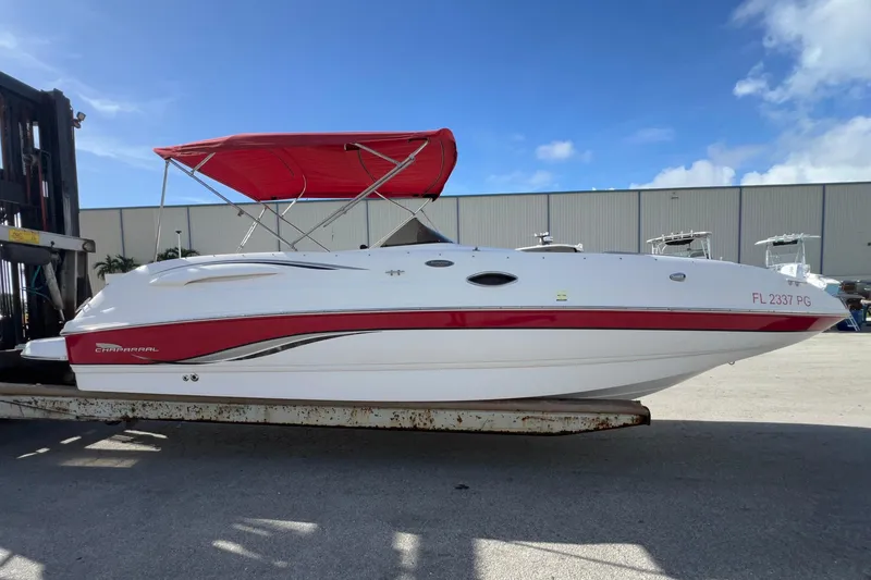Slide: The Image of 2002 Chaparral 232 Sunesta boat with red canopy on a trailer, under clear blue sky. - 3