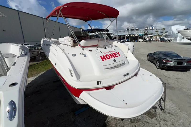 Slide: The Image of 2002 Chaparral 232 Sunesta boat with red canopy, docked outdoors under cloudy sky. - 4