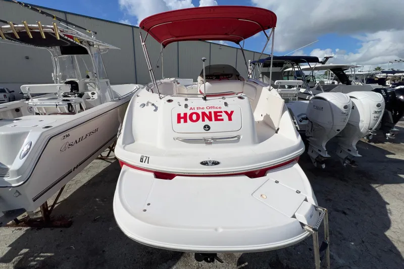 Slide: The Image of 2002 Chaparral 232 Sunesta boat with red canopy, docked alongside other boats. - 6