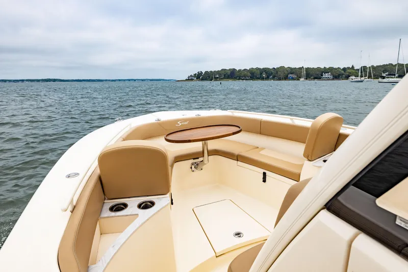 Slide: The Image of 2021 Scout 277LXF boat with tan seating and table on open water. - 18