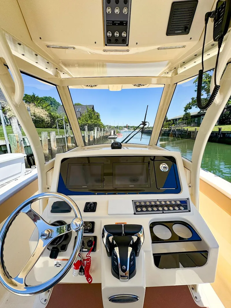 Slide: The Image of 2021 Scout 277LXF boat helm with modern controls and waterfront view. - 2