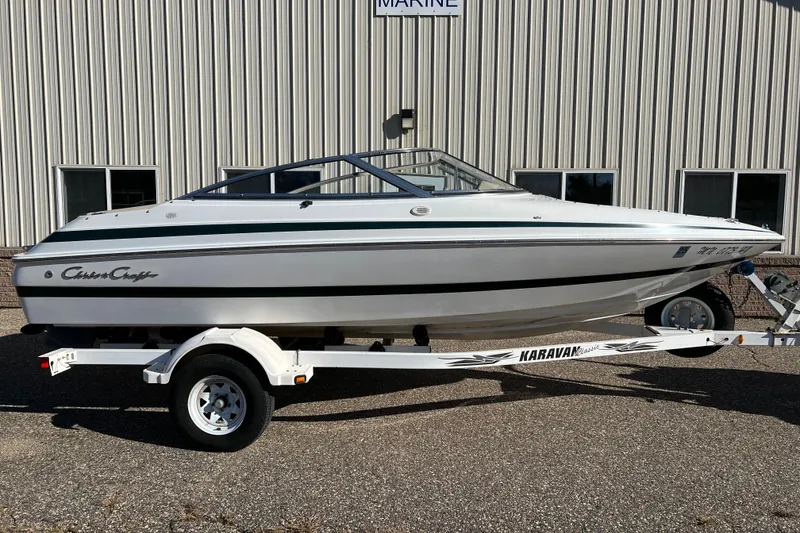 The Image of 1999 Chris-Craft 190 Bowrider boat on trailer, parked outside a building. - 1