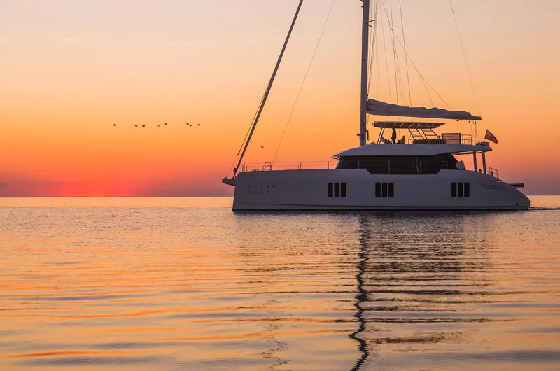 Slide: The Image of 2026 Sunreef 70 yacht sailing at sunset on calm waters. - 3