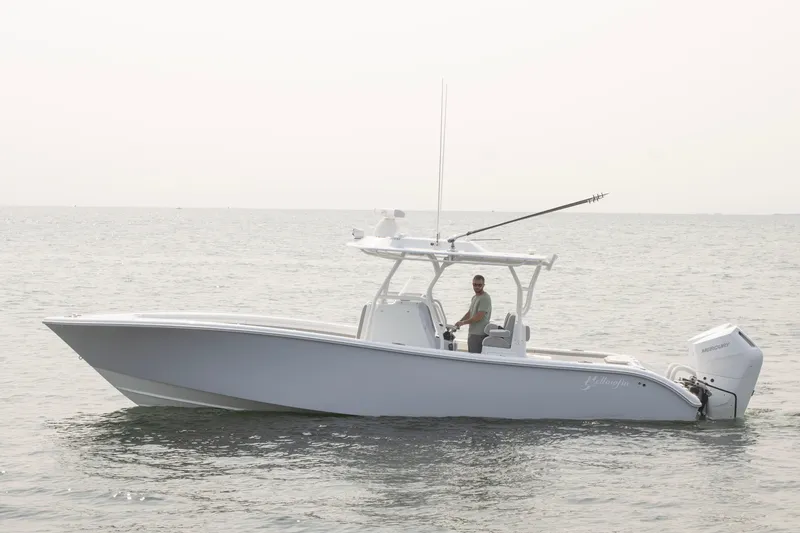 Slide: The Image of 2025 Yellowfin 32 Offshore boat on calm sea with a person at the helm. - 2