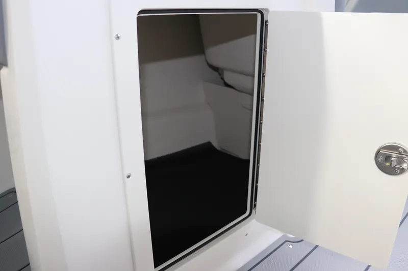 Slide: The Image of 2026 Chaparral 21 SSi OB boat storage compartment with open door and latch. - 44