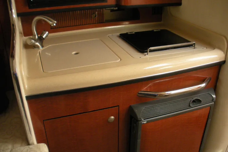 Slide: The Image of 2005 Sea Ray 280 Sundancer galley with sink, stove, and compact fridge. - 5