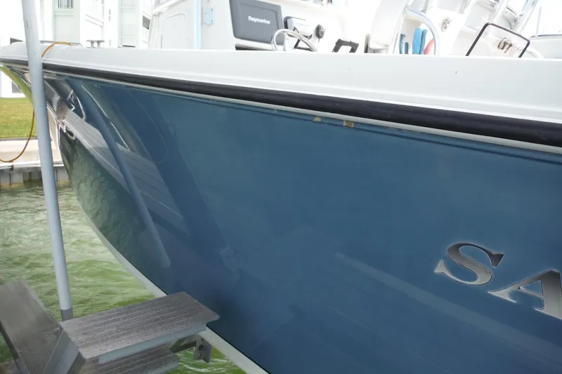 Slide: The Image of 2008 Sailfish 2660 CC boat docked, showcasing sleek blue hull and partial interior view. - 50