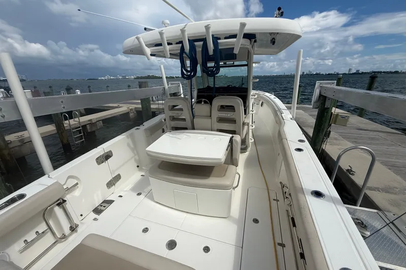 Slide: The Image of 2016 Boston Whaler 330 Outrage boat docked, showcasing spacious deck and seating area. - 10