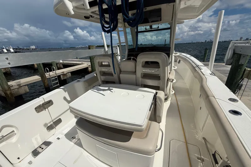 Slide: The Image of 2016 Boston Whaler 330 Outrage boat interior at dock, featuring seating and table. - 12