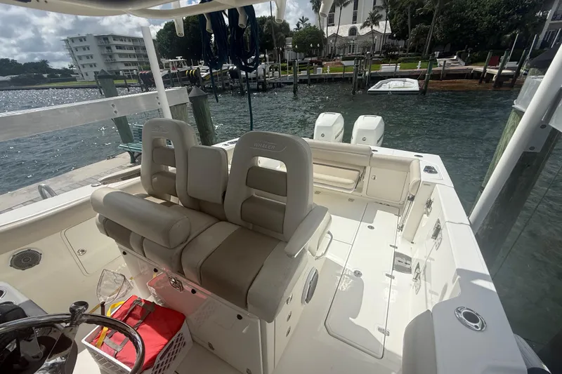 Slide: The Image of 2016 Boston Whaler 330 Outrage boat interior at dock, featuring seating and dual engines. - 13