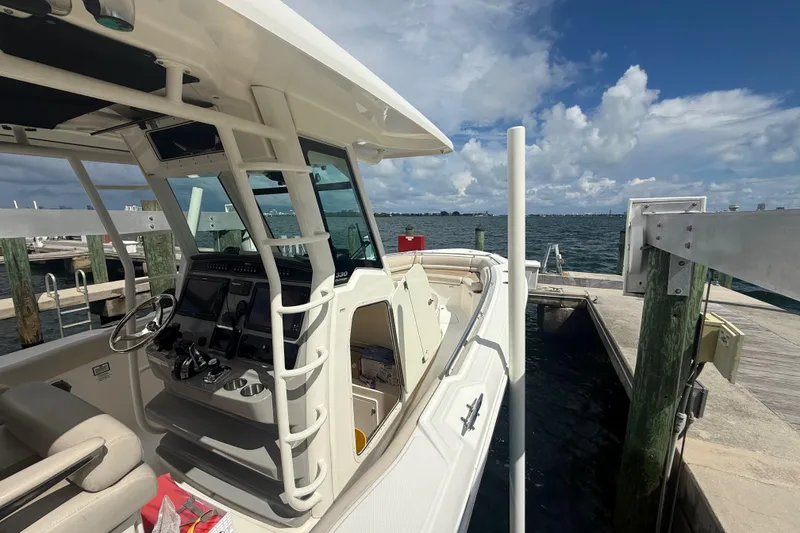 Slide: The Image of 2016 Boston Whaler 330 Outrage docked, showcasing helm and seating, under a partly cloudy sky. - 19