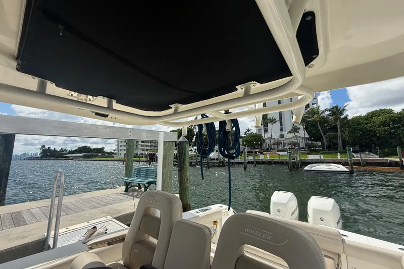 Slide: The Image of 2016 Boston Whaler 330 Outrage at dock, scenic waterfront view, palm trees, and buildings. - 20
