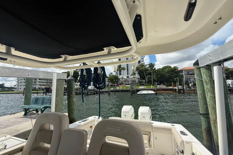 Slide: The Image of 2016 Boston Whaler 330 Outrage docked, showcasing interior seating and waterfront view. - 26