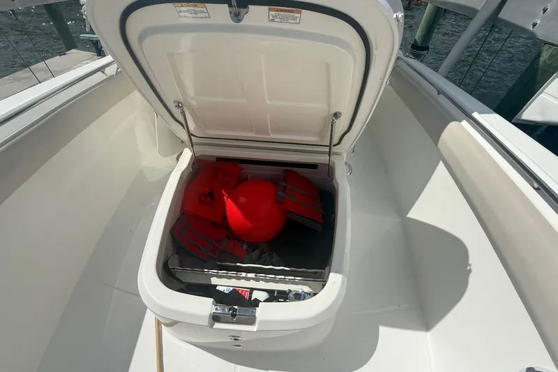 Slide: The Image of Open storage compartment on 2016 Boston Whaler 330 Outrage with life jackets and buoy. - 29