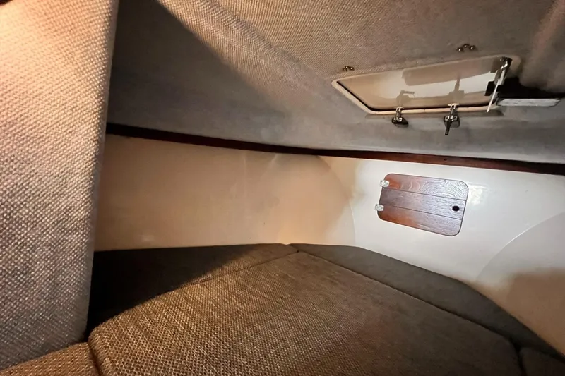 Slide: The Image of Interior cabin of 1989 Shamrock 260 Hardtop boat, featuring cushioned seating and storage hatch. - 21