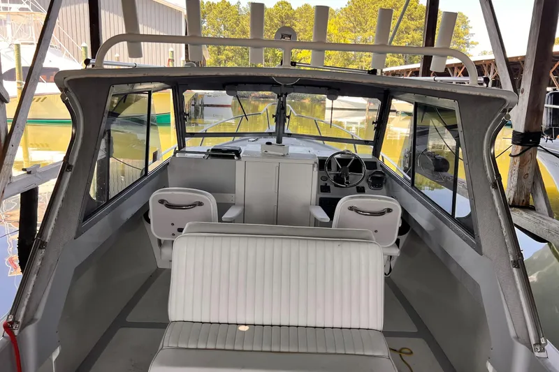 Slide: The Image of 1989 Shamrock 260 Hardtop boat interior with steering wheel and seating in a marina. - 8