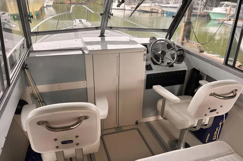 Slide: The Image of 1989 Shamrock 260 Hardtop boat interior with steering wheel and seating in marina setting. - 9
