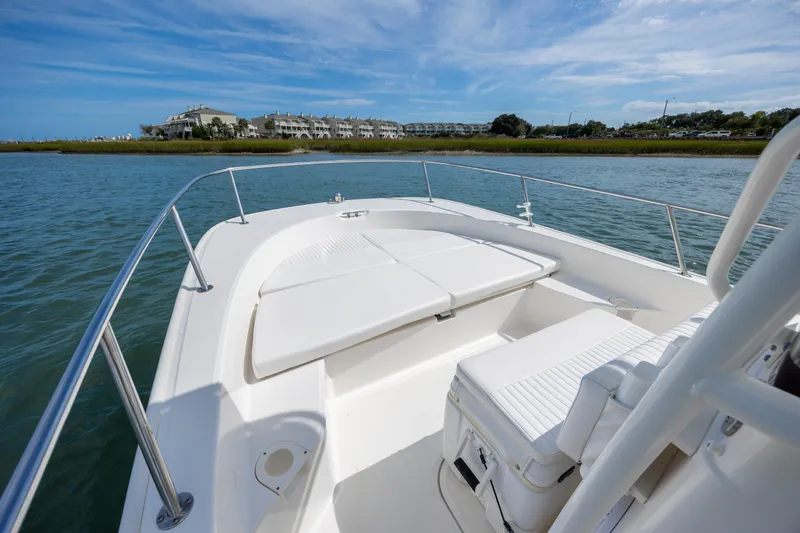 Slide: The Image of 2018 Boston Whaler 210 Montauk boat on calm water, with scenic shoreline view. - 16