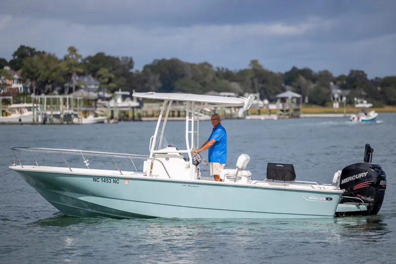 Slide: The Image of 2018 Boston Whaler 210 Montauk boat on water, man steering, Mercury engine visible. - 3