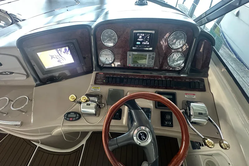 Slide: The Image of 2004 Sea Ray 420 Sundancer helm with navigation controls and wooden steering wheel. - 45