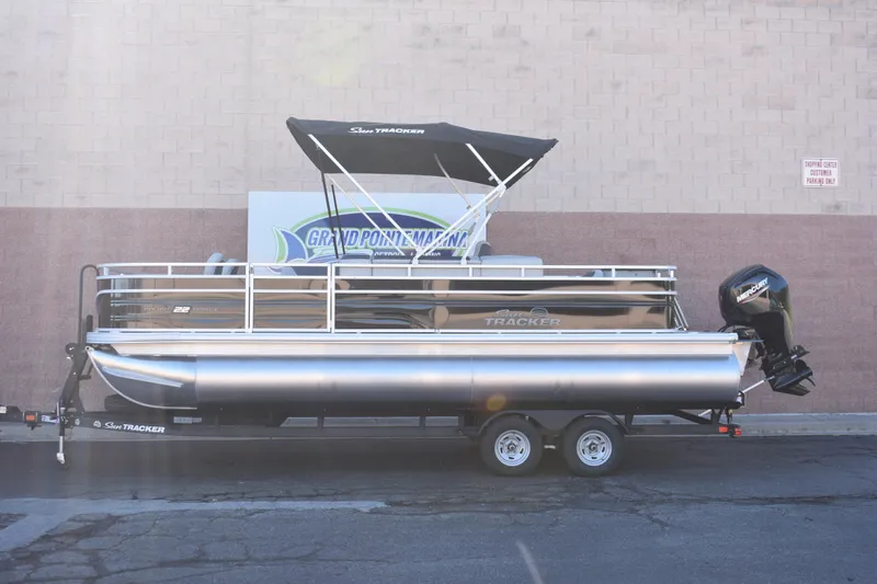 The Image of 2026 Sun Tracker Fishin' Barge 22 DLX pontoon boat on trailer, side view. - 0
