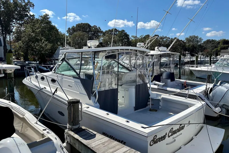 The Image of 2002 Wellcraft 330 Coastal boat docked in a marina under a clear blue sky. - 0