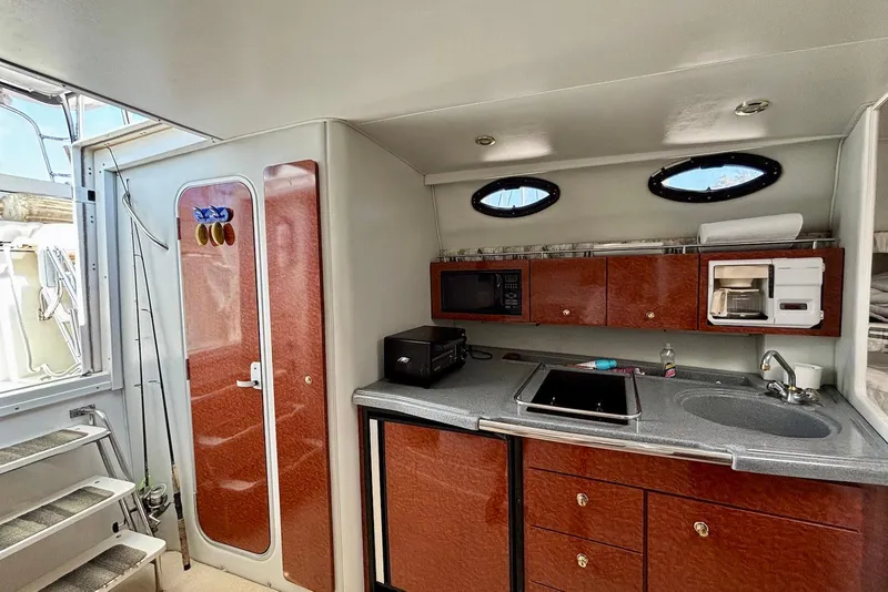 Slide: The Image of 2002 Wellcraft 330 Coastal boat interior with kitchenette, featuring wood cabinets and appliances. - 11