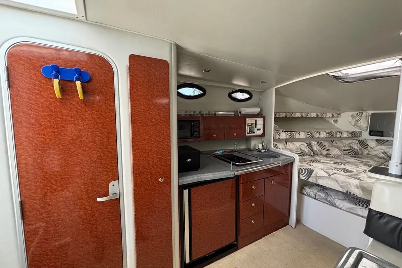 Slide: The Image of 2002 Wellcraft 330 Coastal interior with kitchenette, wood cabinets, and patterned seating. - 12