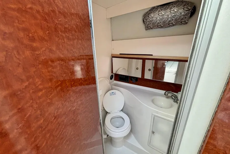 Slide: The Image of 2002 Wellcraft 330 Coastal boat bathroom with wood accents, toilet, sink, and storage. - 14