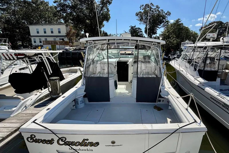 Slide: The Image of 2002 Wellcraft 330 Coastal boat docked, named "Sweet Caroline," with clear skies and surrounding boats. - 7