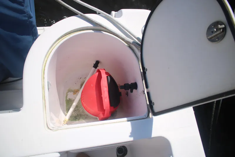 Slide: The Image of Open storage compartment on 2011 Larson Carbiro 240 boat with red container inside. - 19